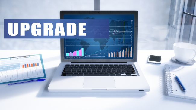 image of a laptop and tablet showing graphs to represent a business environment. the word upgrade is the headline text