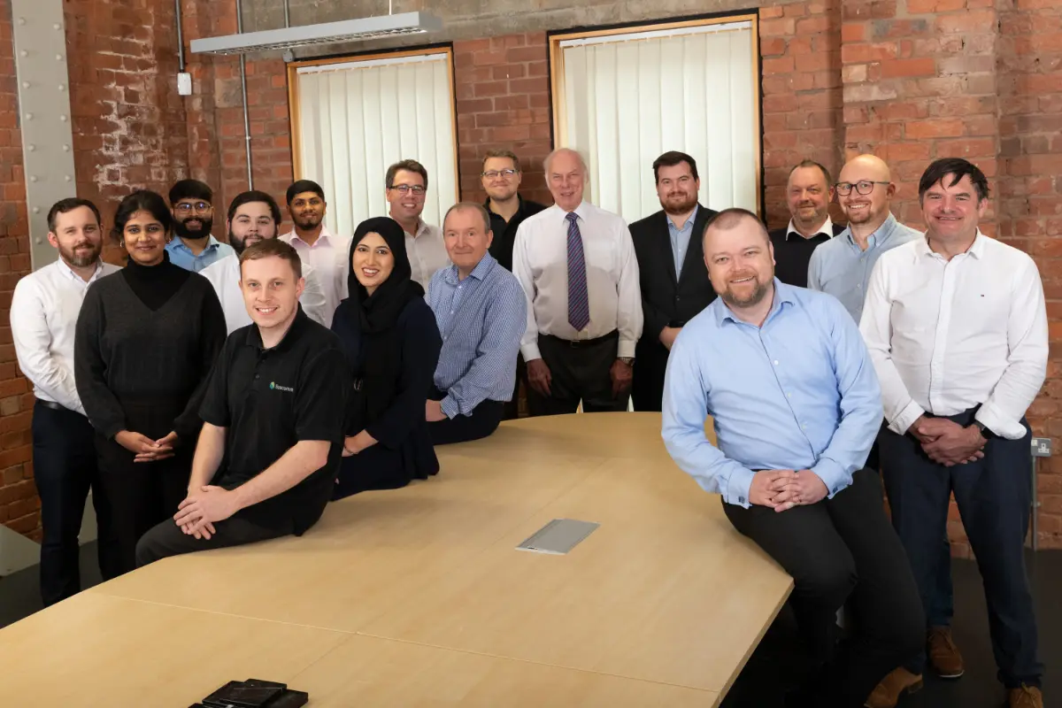 Syscomm team gathered together for team photo around meeting table at office in Coventry