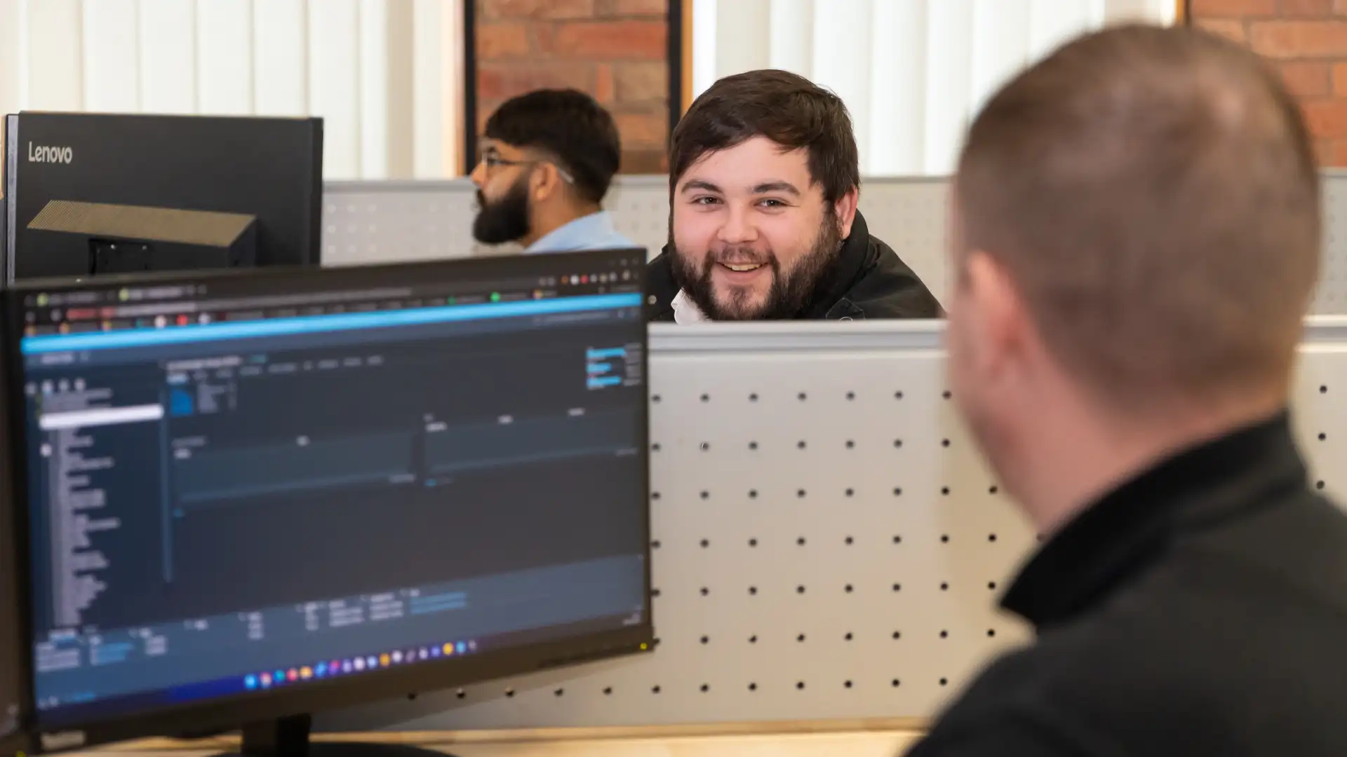 A friendly conversation between IT professionals in an open-plan office