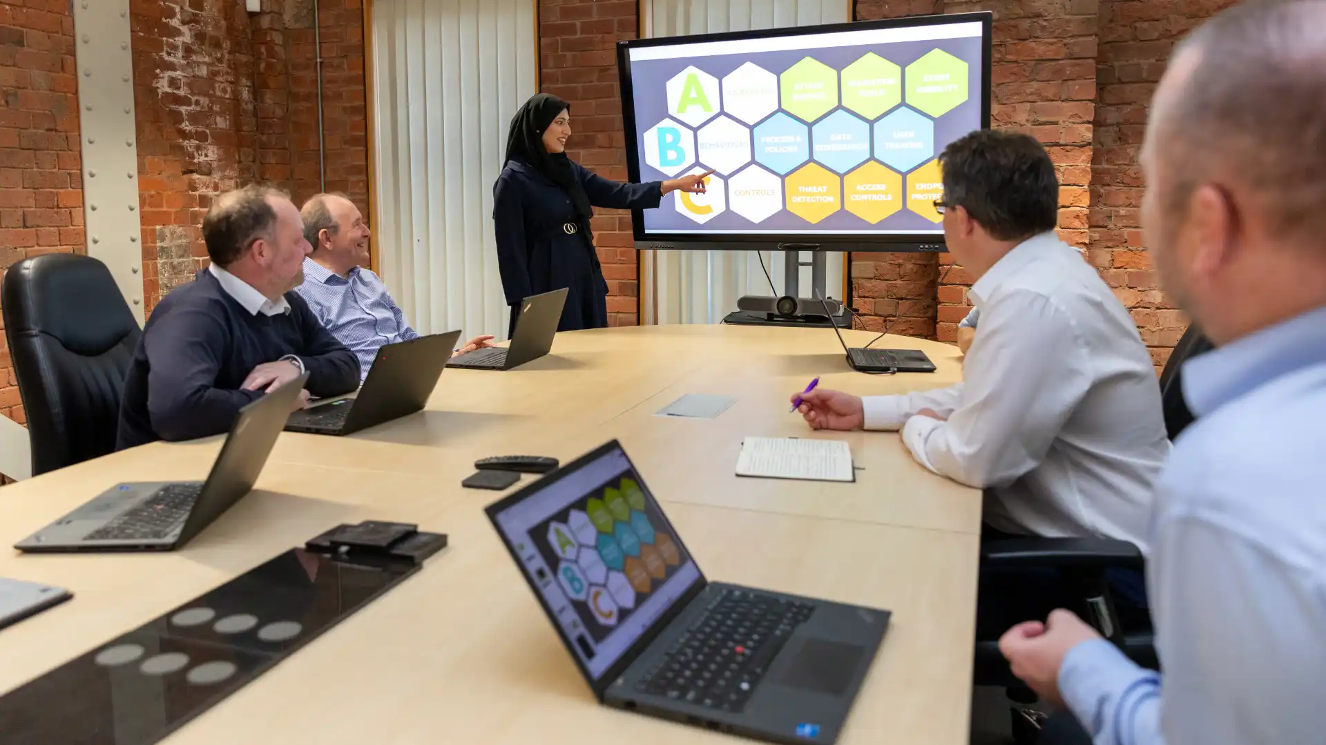 A professional woman presenting on a large screen displaying a hexagonal diagram