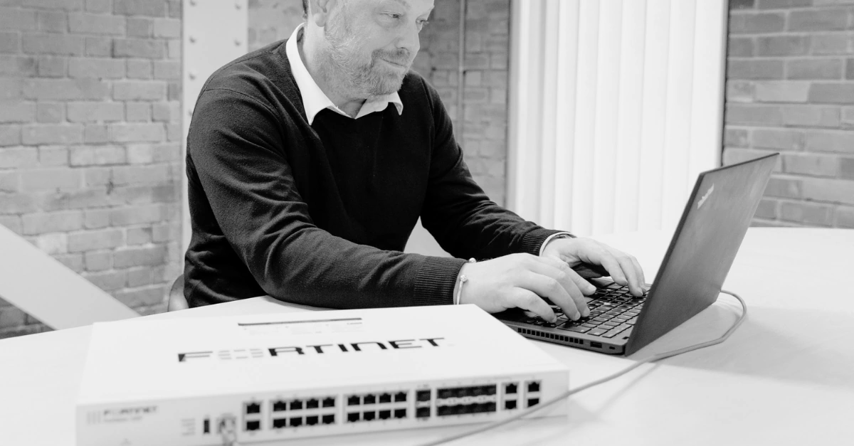 Syscomm engineer configuring a Fortinet firewall on a laptop