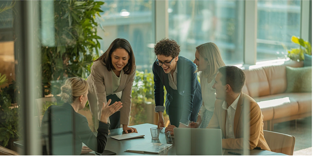 Colleagues collaborating around a laptop in a modern office