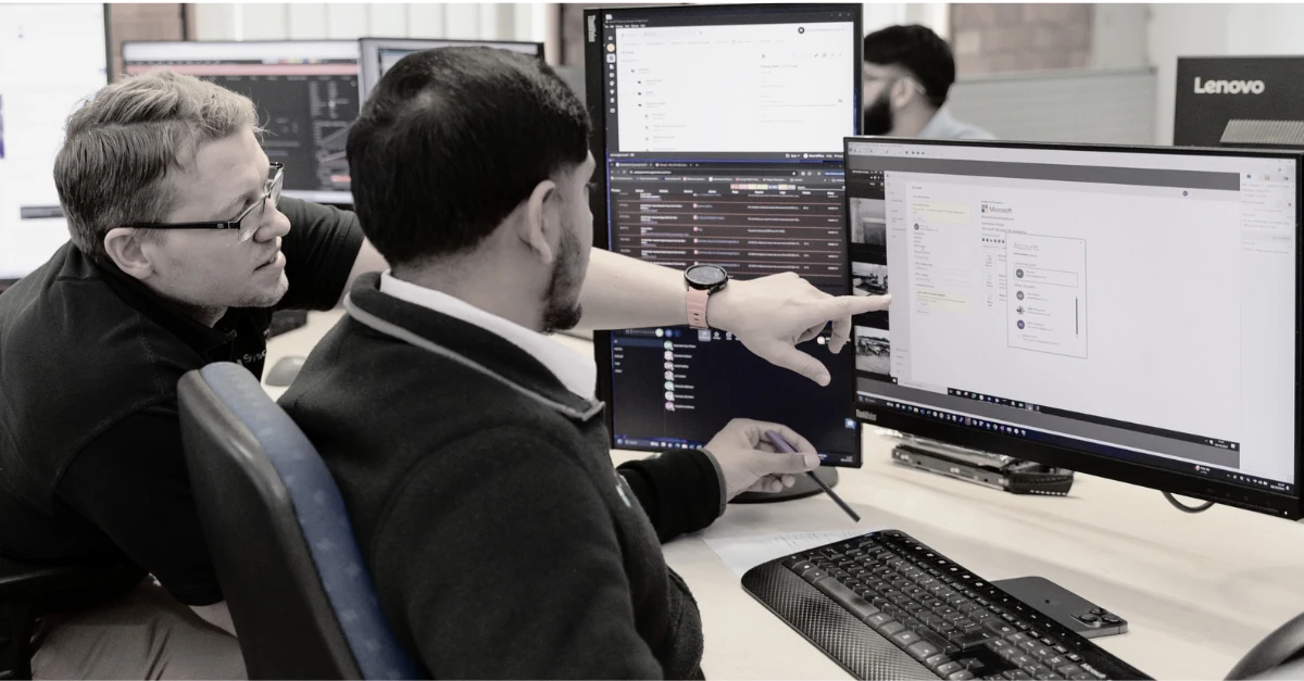 Two Syscomm engineers providing managed IT services on multiple screens