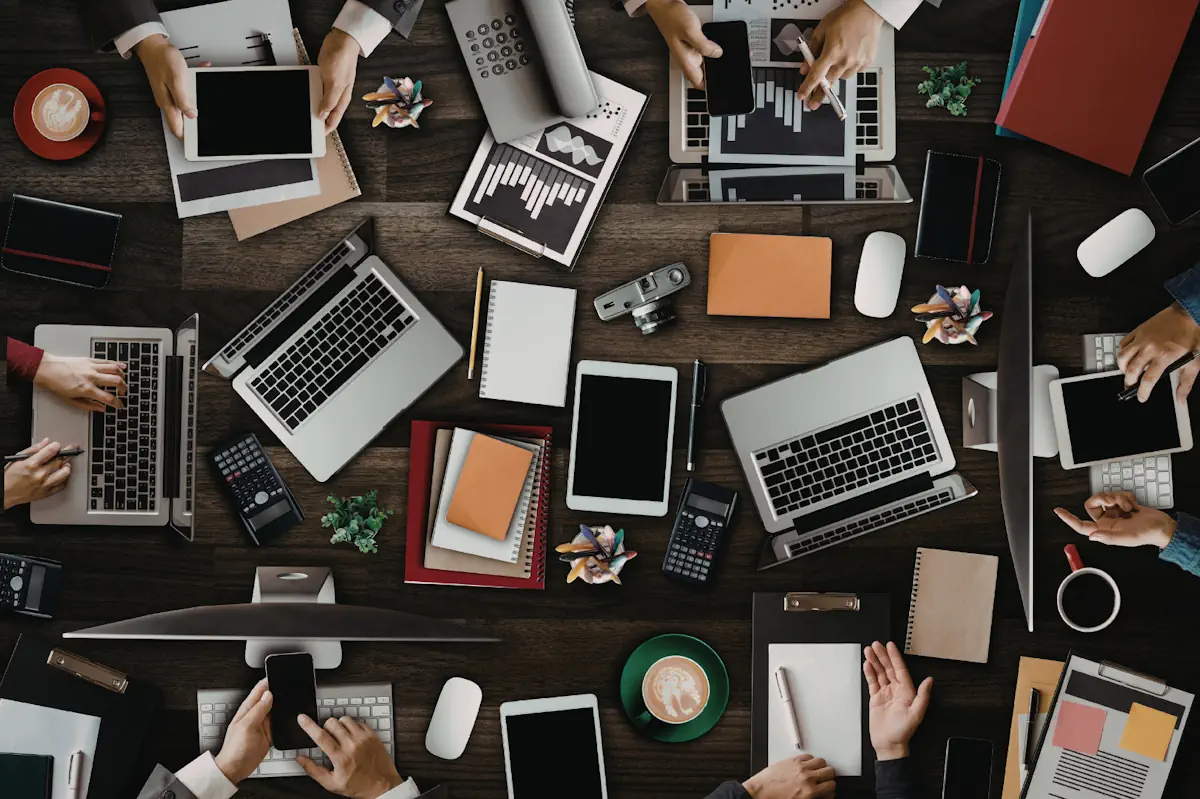 Overhead view of a team working at a table covered in laptops, tablets and smartphones